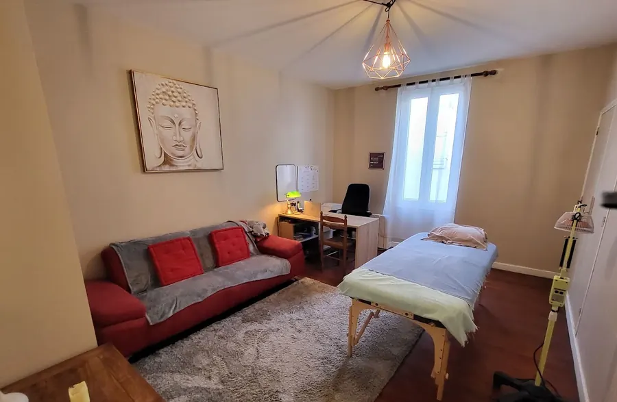 La salle de soin du cabinet Zenergy : table de soin, canapé, parquet ancien et lampe chauffante