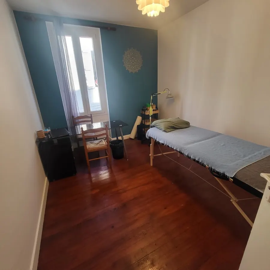 La seconde salle du cabinet, mur bleu-vert et table de soin près de la fenêtre